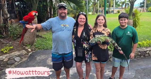 A visiting family holding a scarlet macaw and a green iguana on a Mowatt Tours day out