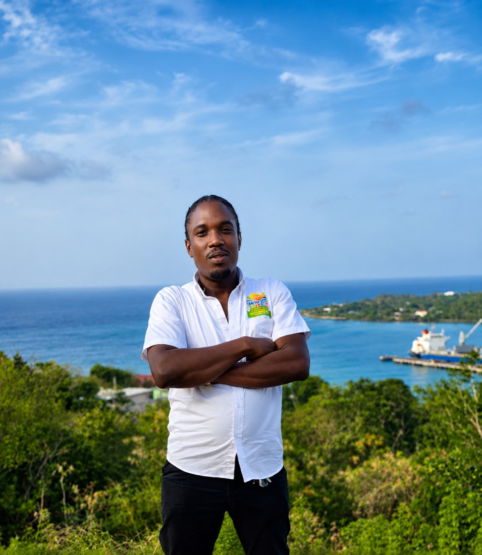 Shavaughn 'Bankz' Mowatt in his Mowatt Tours shirt, arms crossed at a lookout above the harbour